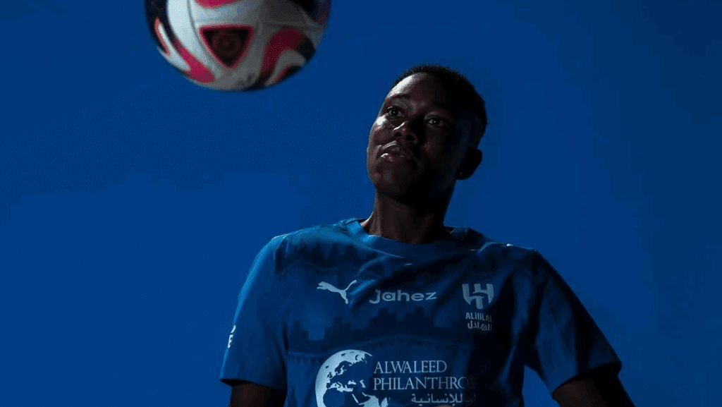 Asisat Oshoala in Al Hilal jersey during her unveiling, controlling a ball against a blue background
